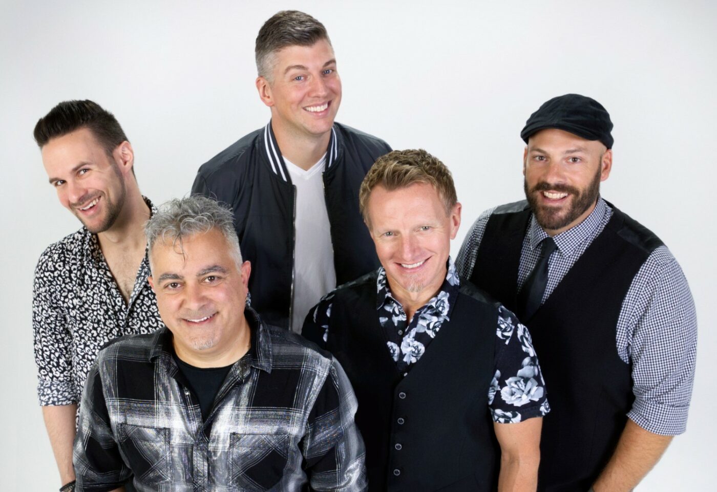 fem män i skjortor i olika mönster, slips och väst ler glatt in i kameran