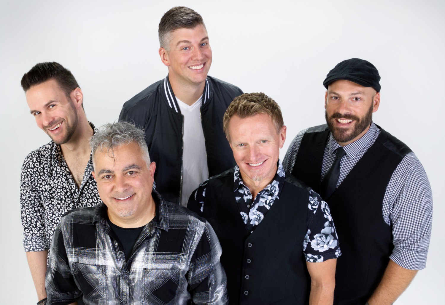 fem män i skjortor i olika mönster, slips och väst ler glatt in i kameran